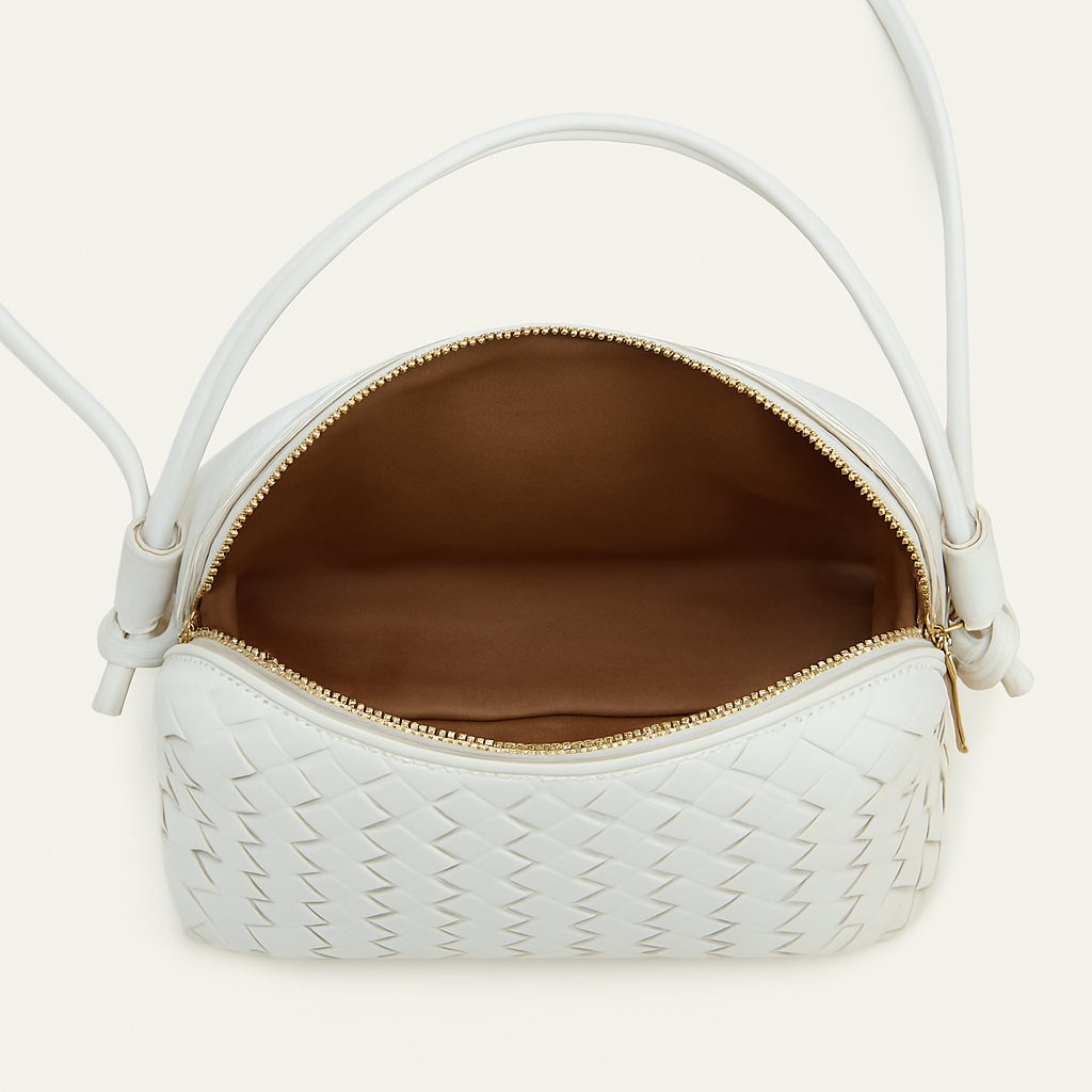 Vista dall'alto dell'interno di una borsa a tracolla bianca intrecciata con fodera interna marrone e zip dorata.
