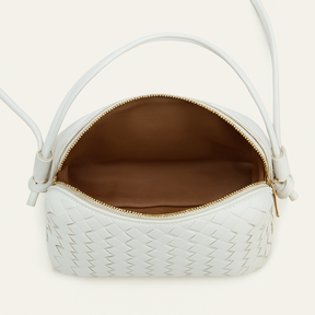 Vista dall'alto dell'interno di una borsa a tracolla bianca intrecciata con fodera interna marrone e zip dorata.