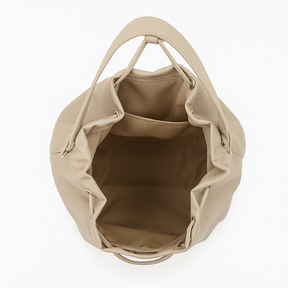 Giovane donna che cammina in citt? con una borsa a secchiello beige indossata sulla spalla